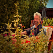 Gentleman sittingin the patio amongst flowers