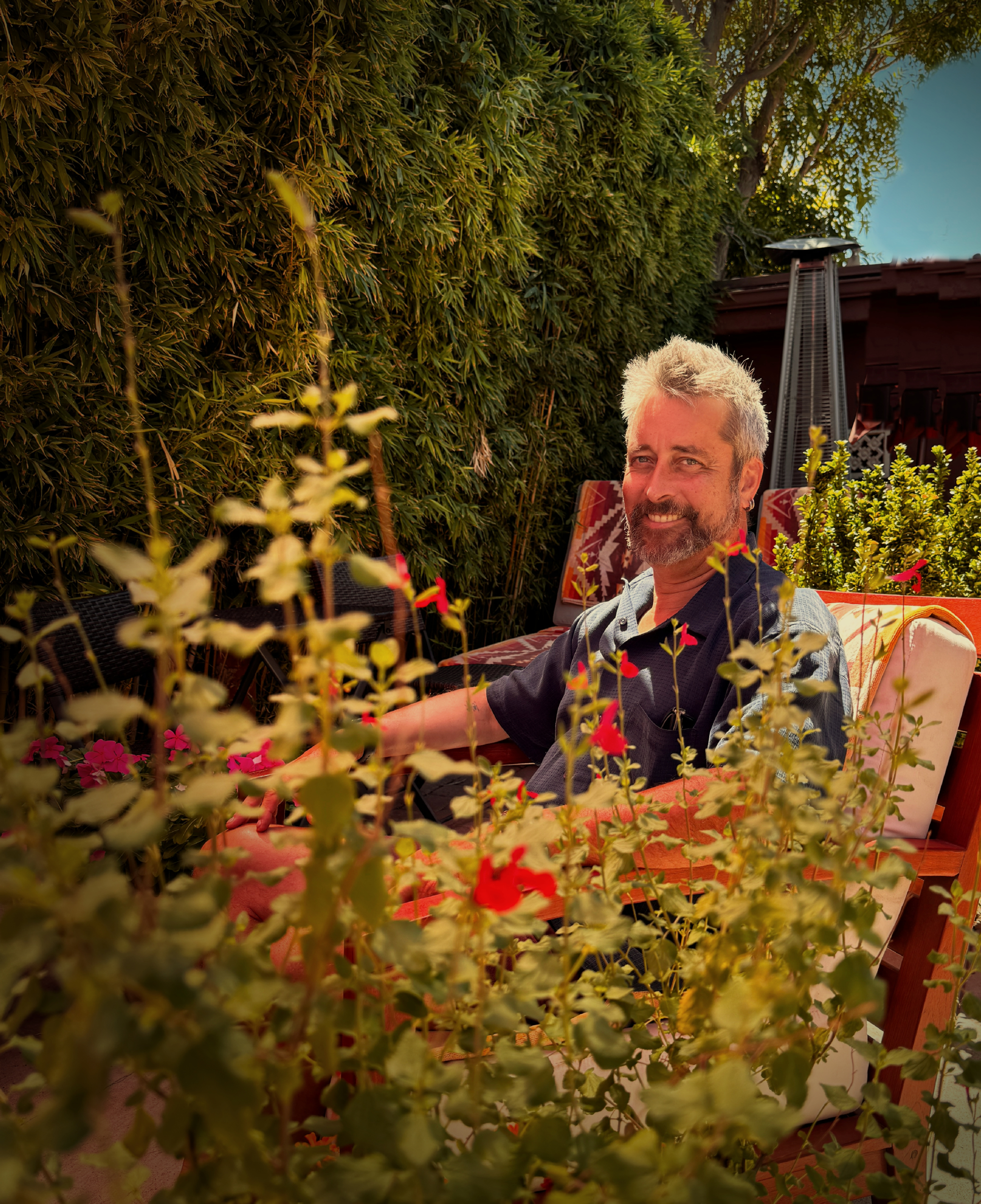 Gentleman sittingin the patio amongst flowers